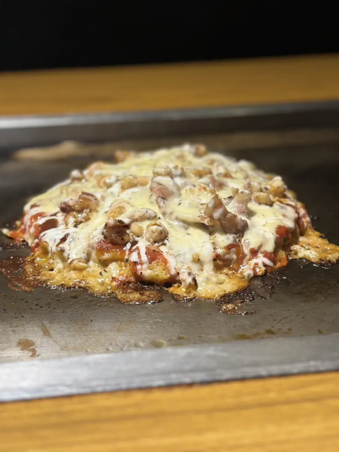 鉄板で焼き上げられたみやこ屋の濃厚ピザ風お好み焼き